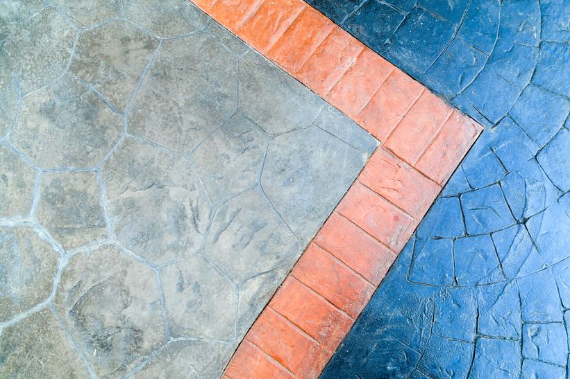 blue stamped concrete and gray stencilled concrete with orange stencilled concrete edgework dividing the two colours and finishes